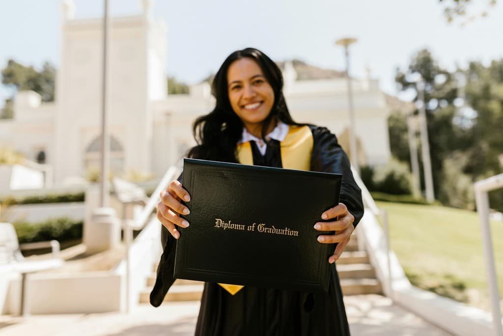 A smiling graduate holding her diploma on a university campus