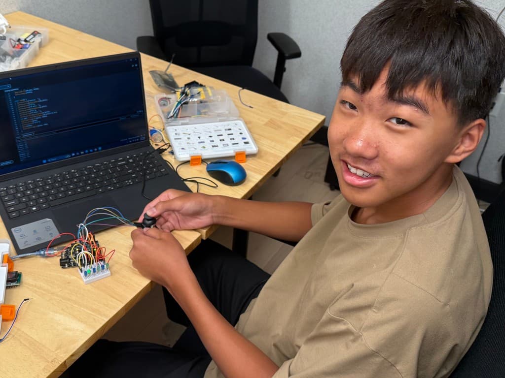 A student wiring an electronics project at a laptop